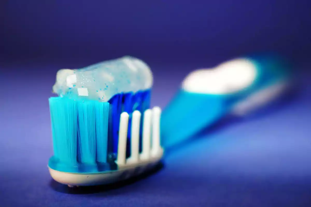 Un cepillo de dientes azul con pasta dental sobre un fondo azul.