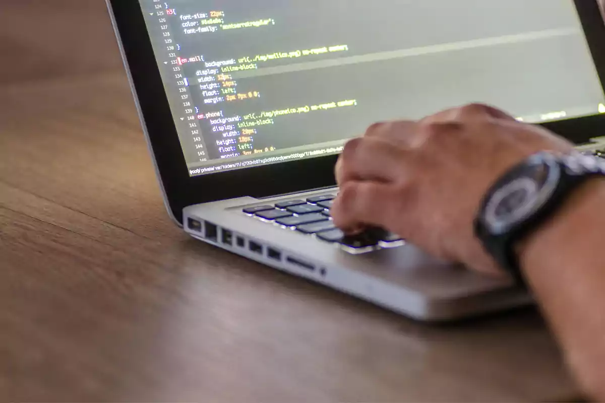 Persona usando una laptop mientras escribe código en la pantalla
