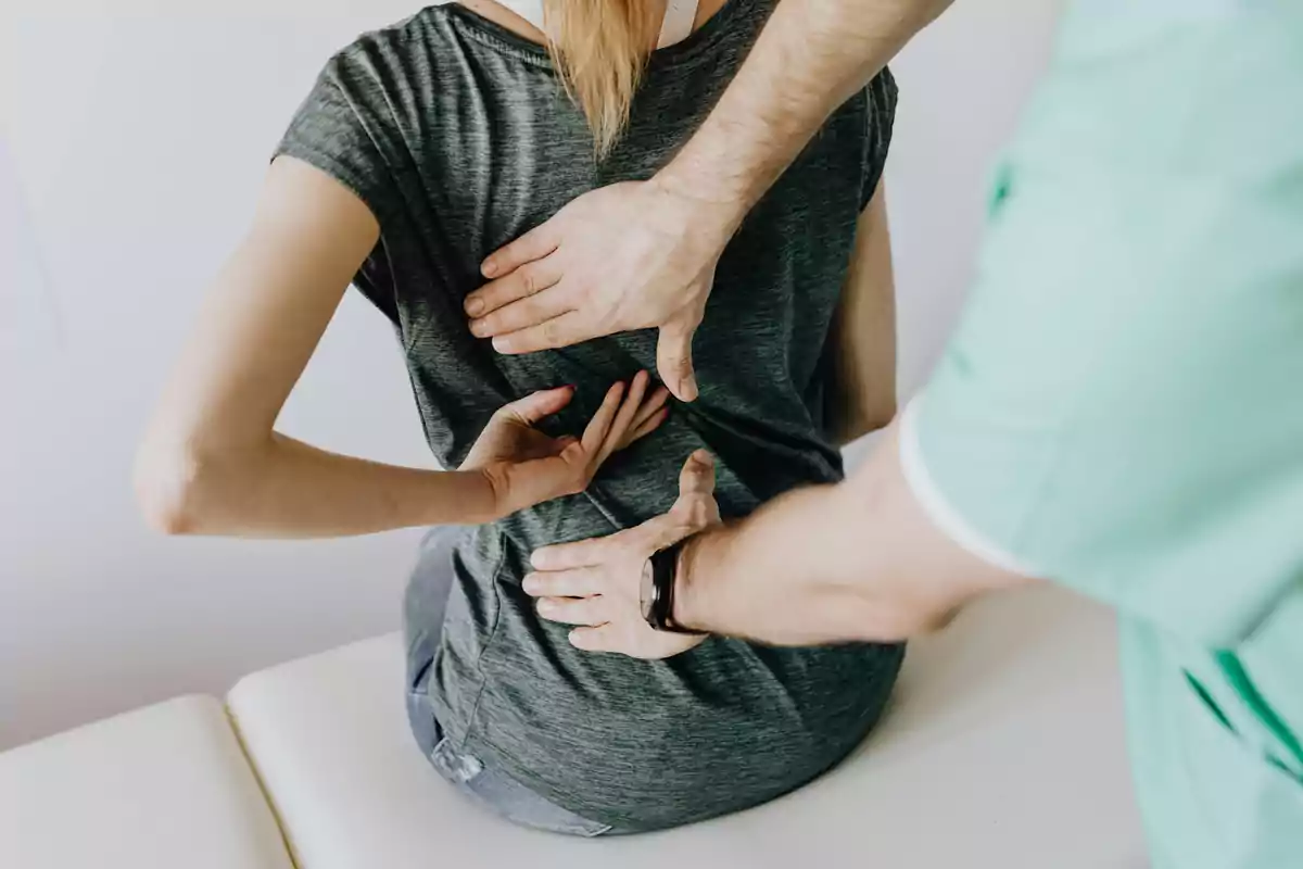 Persona recibiendo terapia física en la espalda por parte de un profesional.