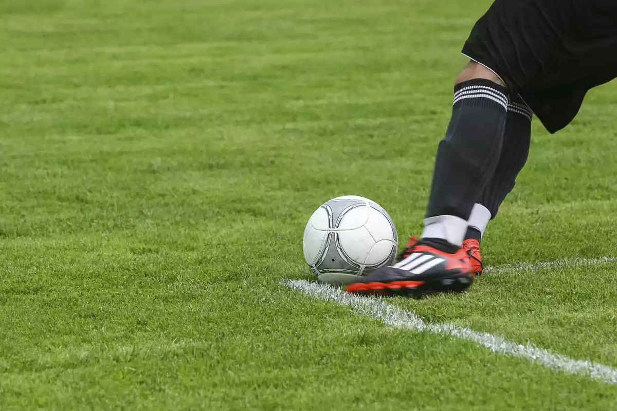 Un jugador de fútbol pateando un balón en el campo.