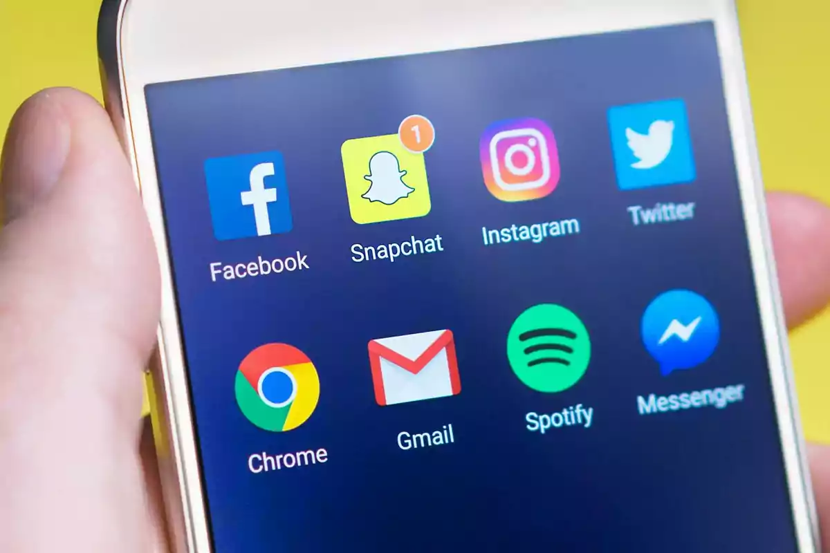 Pantalla de un teléfono móvil mostrando los íconos de aplicaciones populares como Facebook, Snapchat, Instagram, Twitter, Chrome, Gmail, Spotify y Messenger.