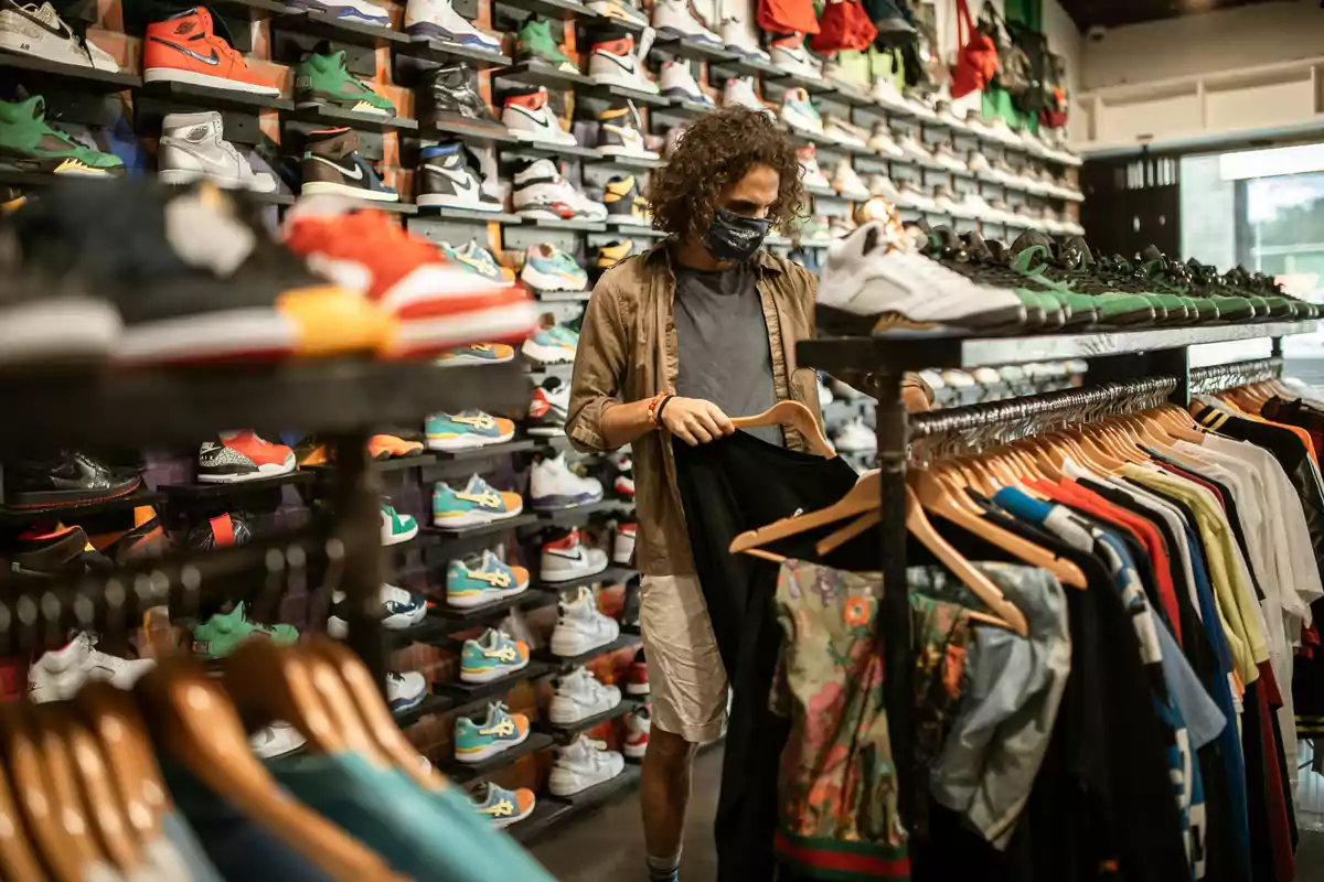 Persona con mascarilla comprando ropa en una tienda de zapatillas deportivas.