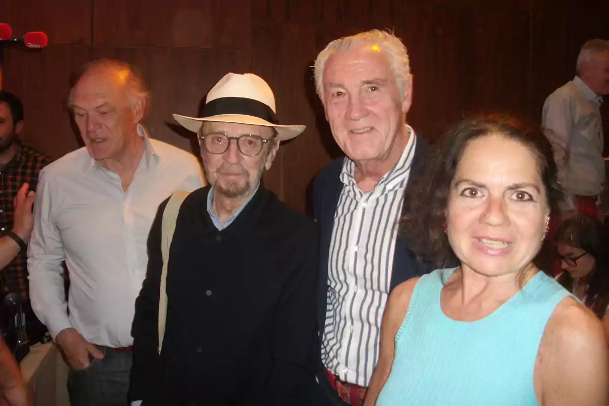 Cuatro personas posan juntas en un evento social en un ambiente interior con paredes de madera. Cuatro personas posan juntas en un evento social en un ambiente interior con paredes de madera.