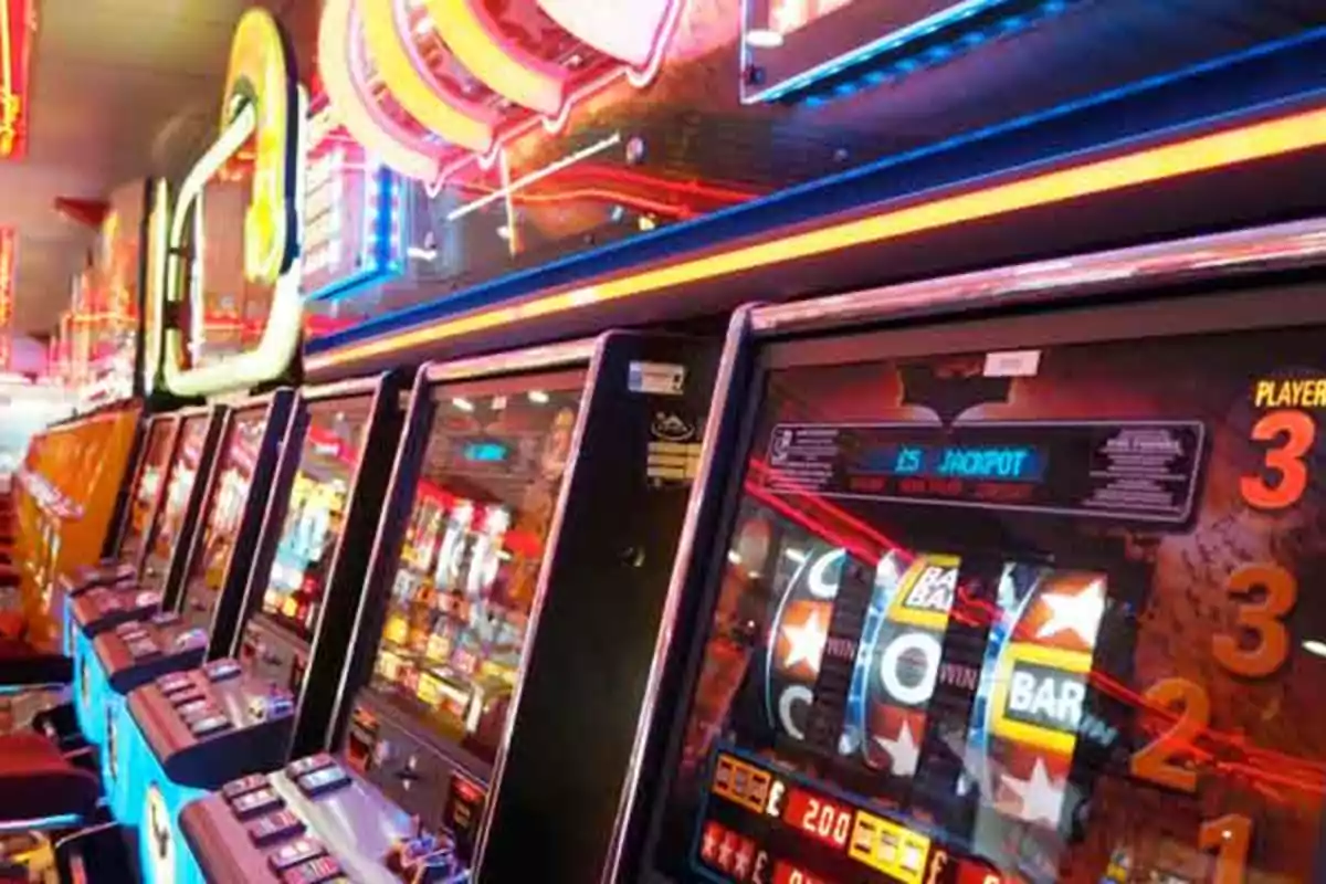 Máquinas tragamonedas alineadas en un casino con luces de neón brillantes.