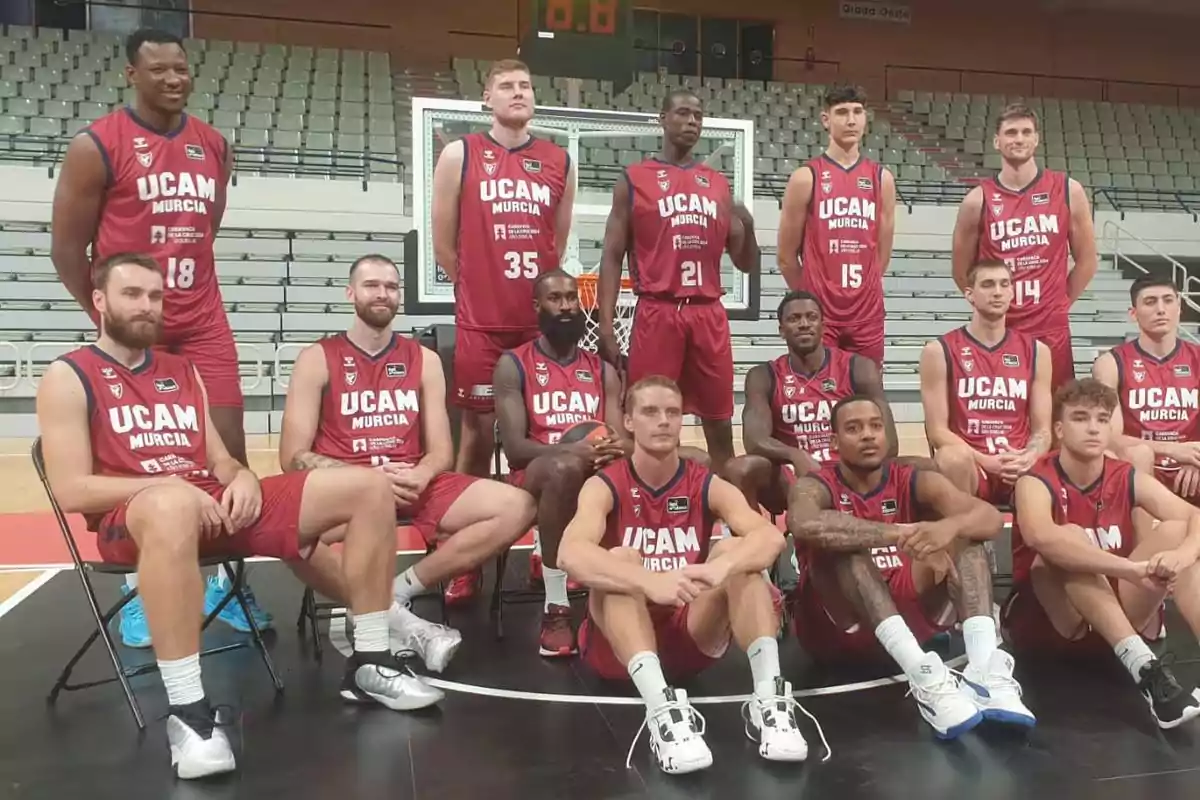 Jugadores del equipo de baloncesto UCAM Murcia posando para una foto de equipo en una cancha de baloncesto.