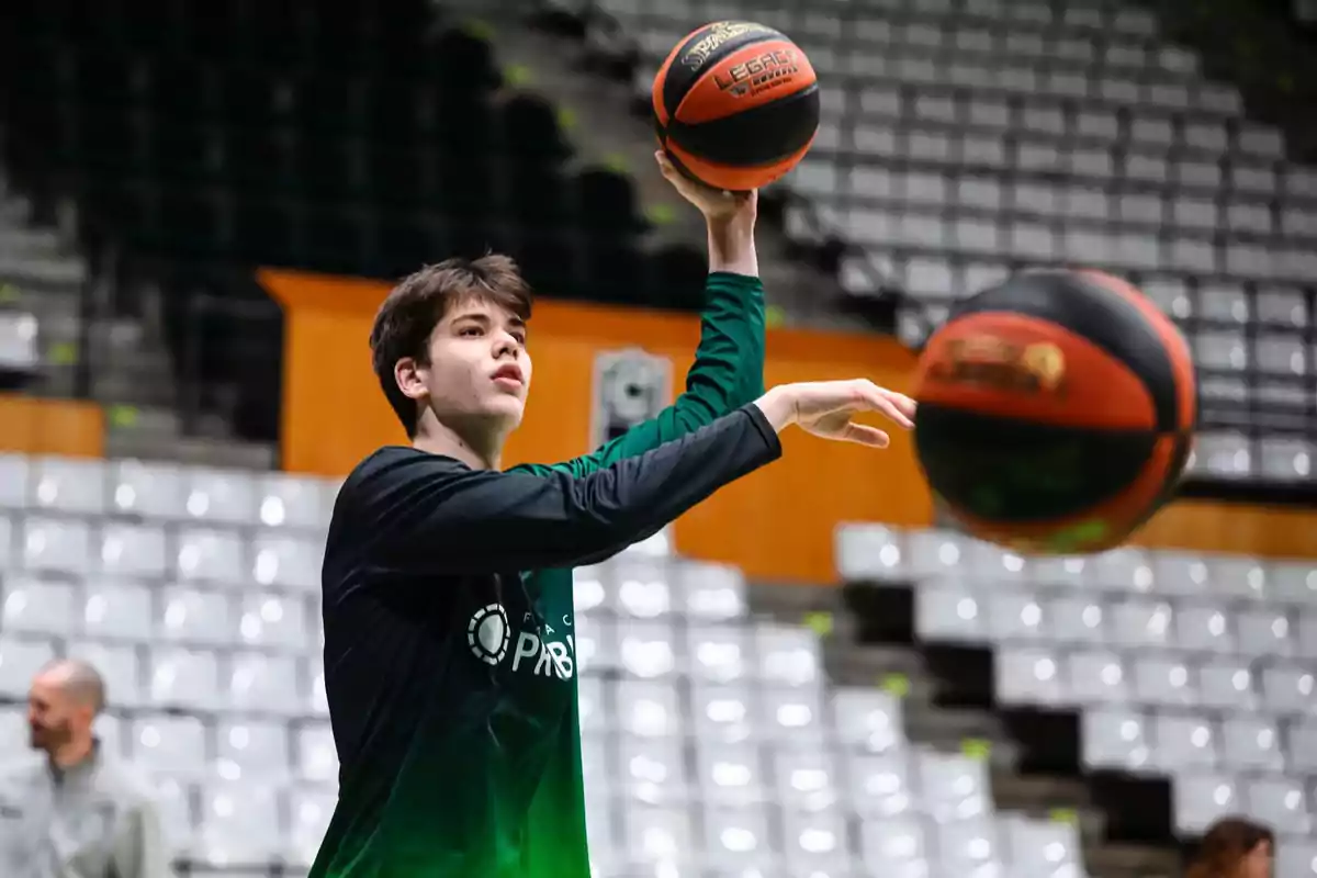 Joven lanzando una pelota de baloncesto en una cancha con gradas vacías al fondo
