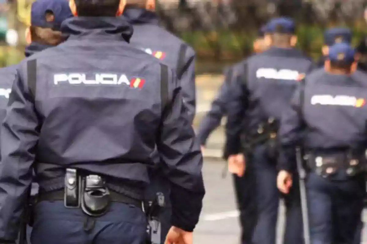 Policías caminando en fila con uniformes azules.