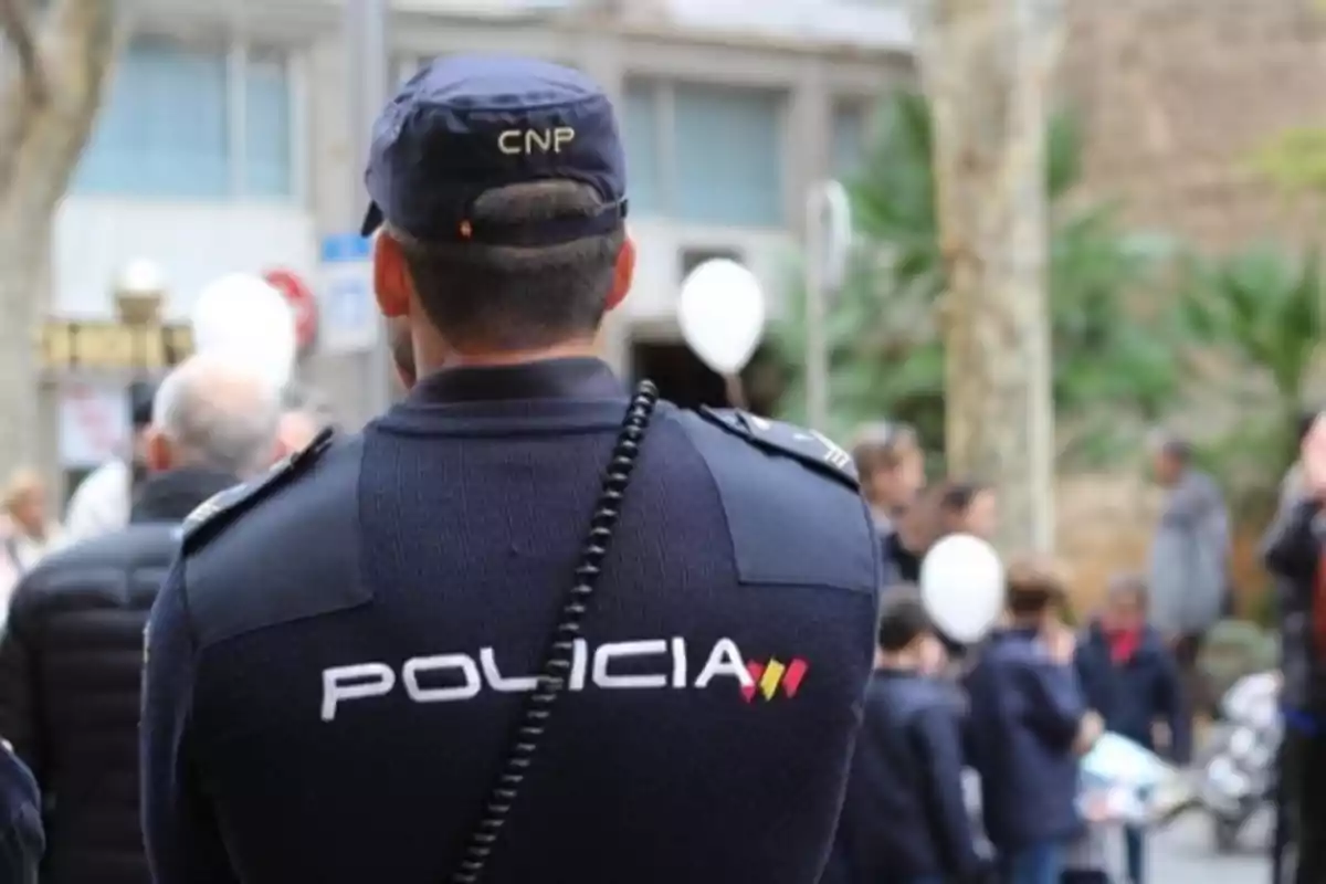 Un policía de espaldas con uniforme del Cuerpo Nacional de Policía en un evento público.