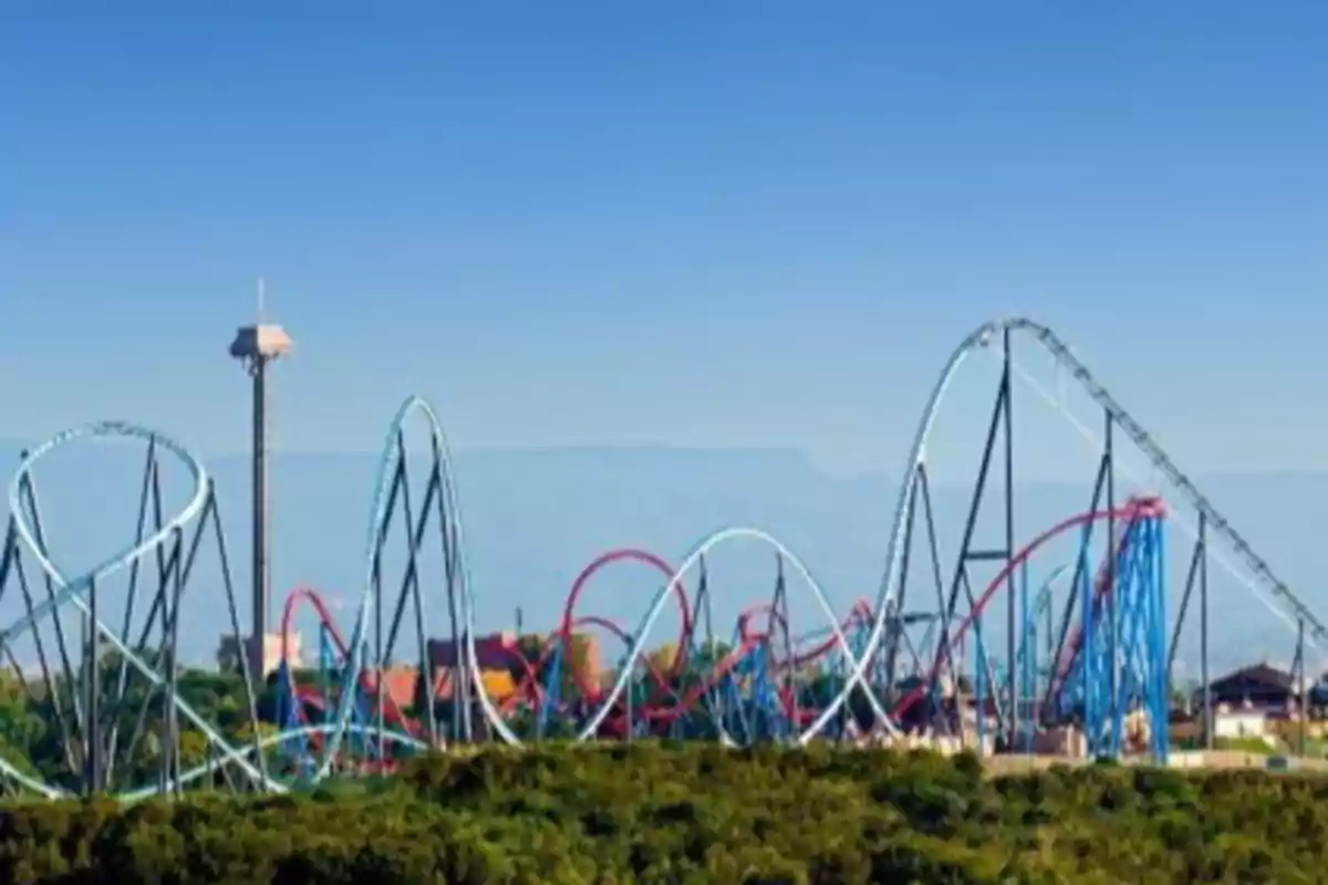 Una montaña rusa con múltiples curvas y una torre de observación en un parque de atracciones.