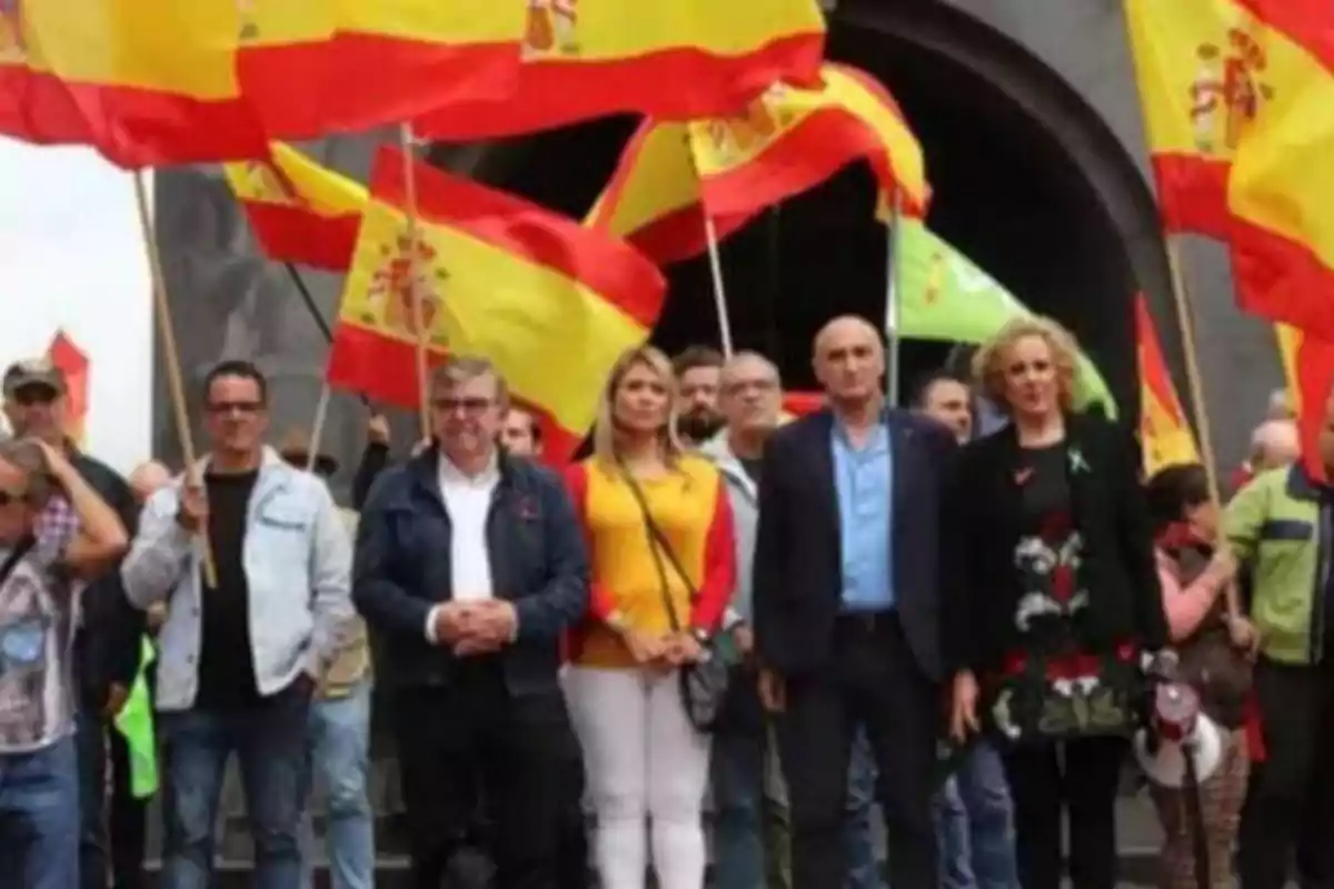 Un grupo de personas sosteniendo banderas de España en una manifestación.
