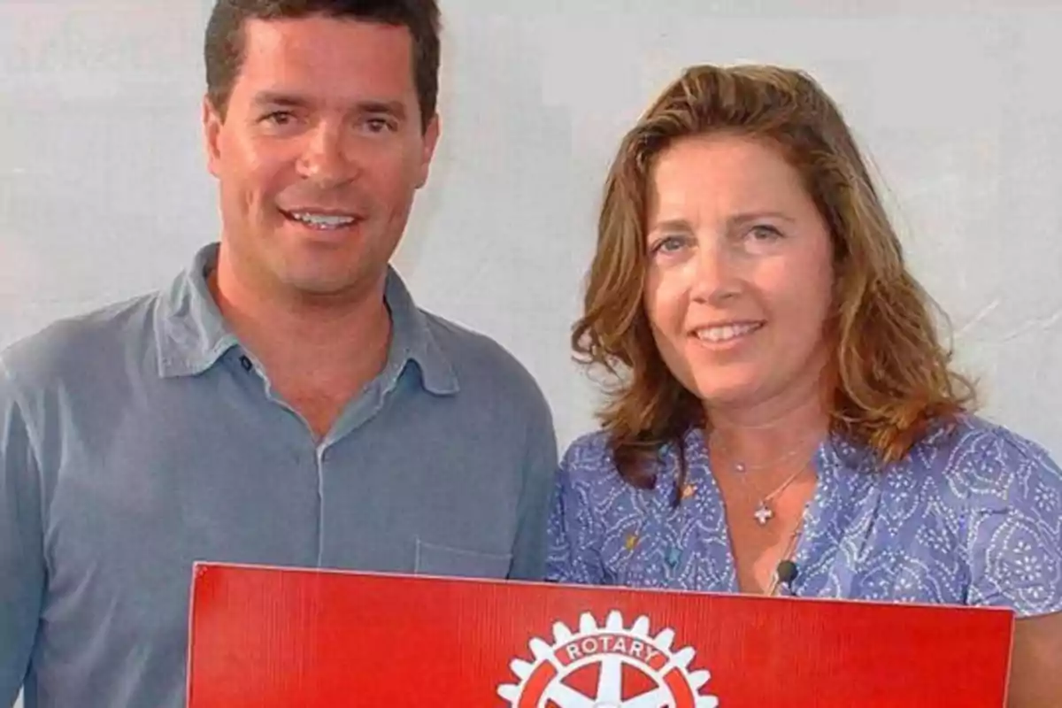 Dos personas posando con un cartel del Rotary Club.
