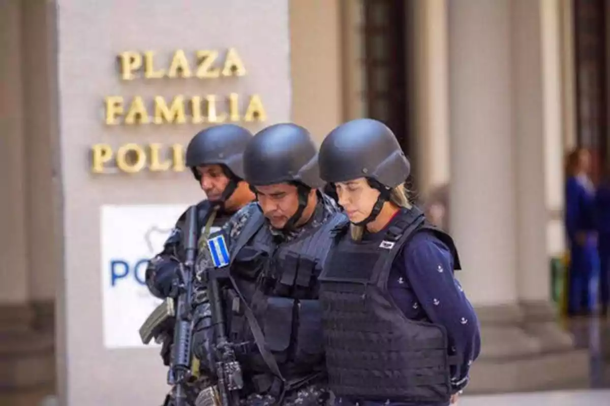 Tres personas con equipo táctico y cascos están de pie frente a un edificio con un letrero que dice "PLAZA FAMILIA POLI".