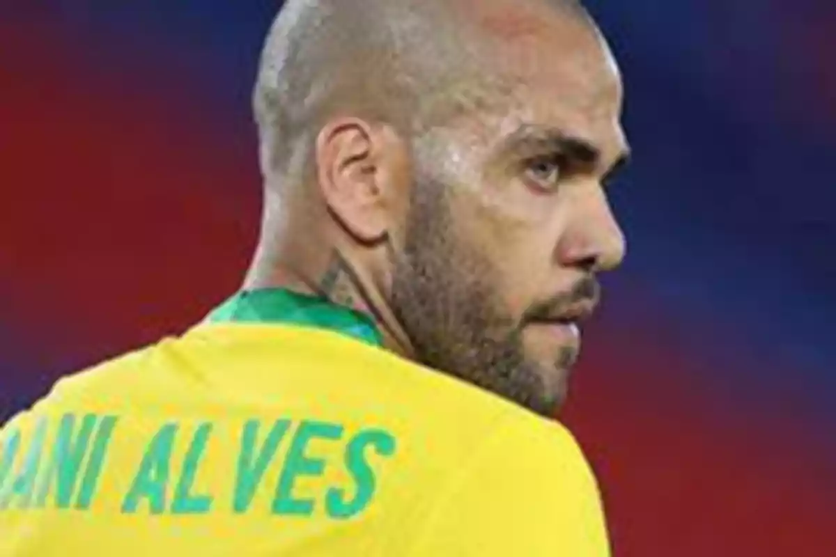 Un jugador de fútbol con camiseta amarilla y verde mirando hacia la derecha.