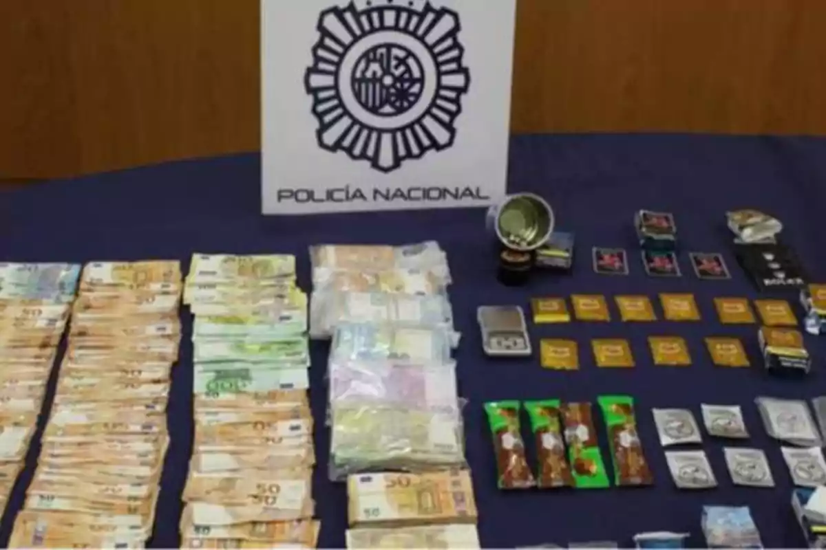 Dinero en efectivo, drogas y otros objetos incautados por la Policía Nacional sobre una mesa.