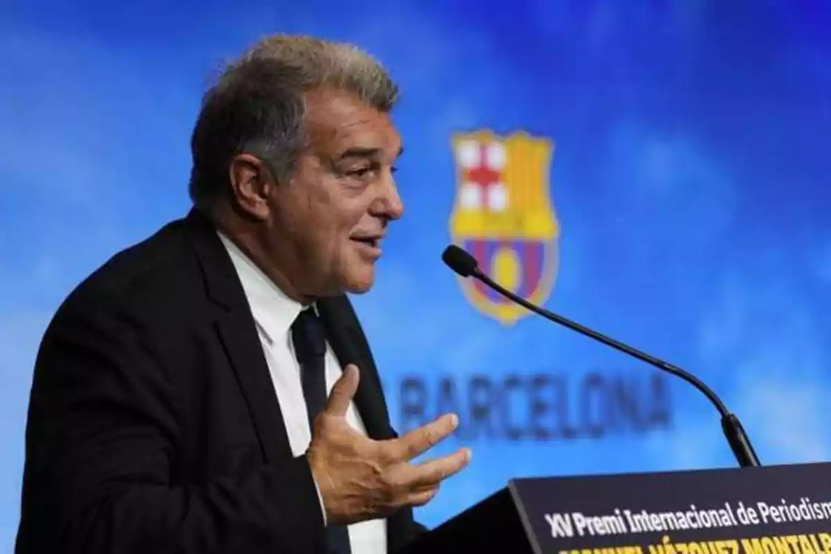 Un hombre hablando en un podio con el logo del FC Barcelona en el fondo.