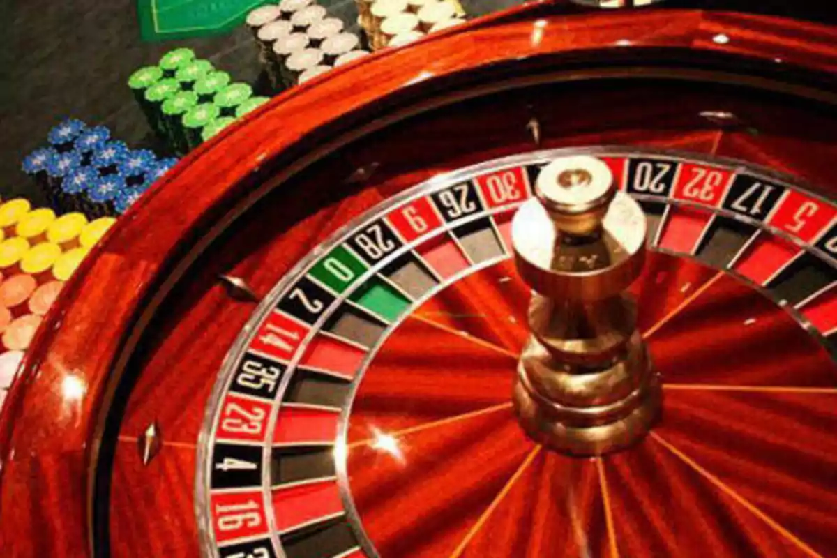 Rueda de ruleta de casino con fichas de diferentes colores en el fondo.