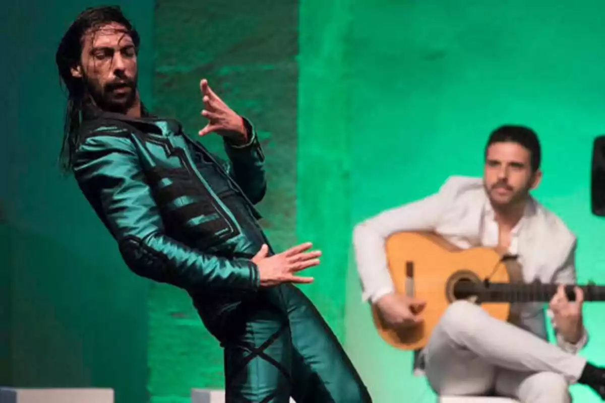 Un bailarín de flamenco en una pose dramática mientras un guitarrista toca en el fondo.