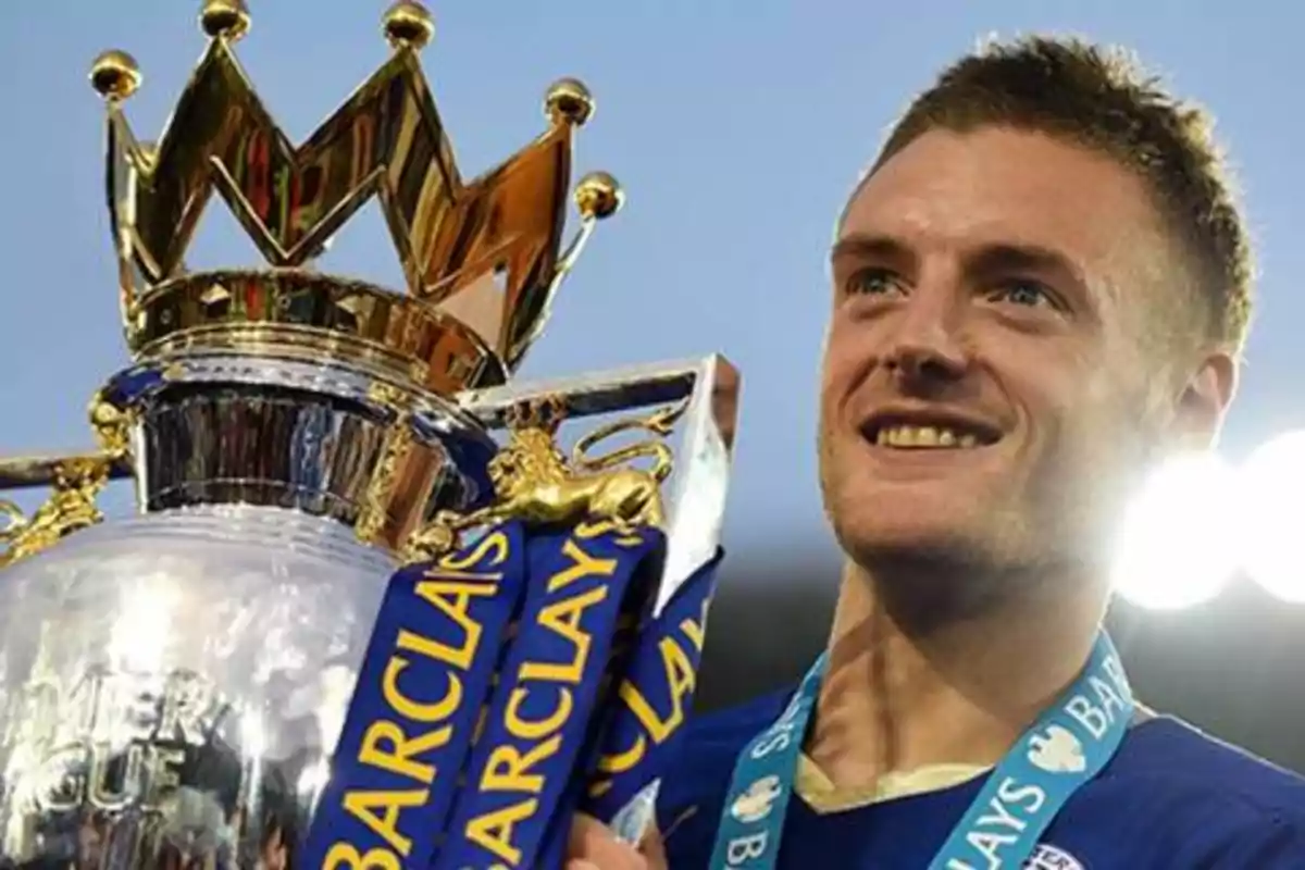 Un jugador de fútbol sonríe mientras sostiene el trofeo de la Premier League Barclays.