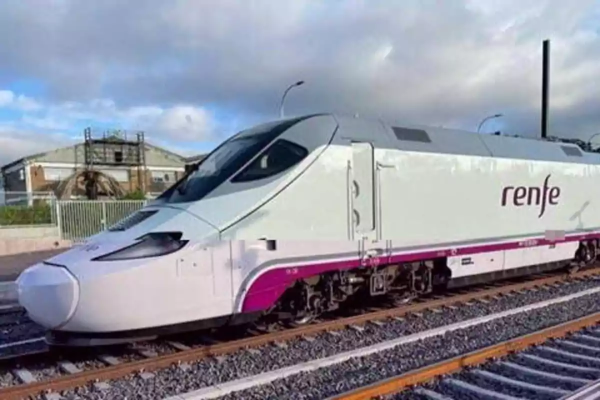 Un tren de alta velocidad de la compañía Renfe en una vía férrea con un cielo parcialmente nublado de fondo.