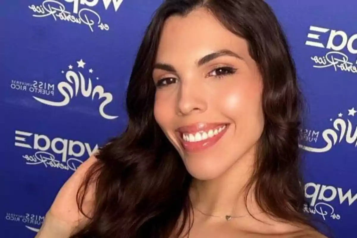 Una mujer sonriente con cabello largo y ondulado frente a un fondo azul con logotipos y texto.