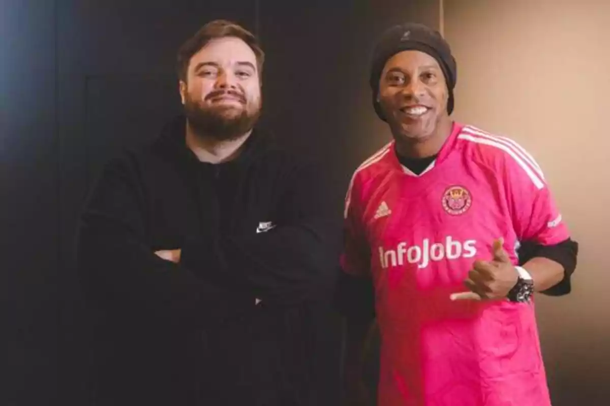 Dos personas posando, una con sudadera negra y otra con camiseta de fútbol rosa.