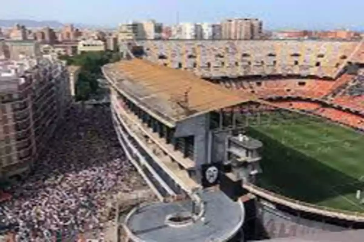 Vista aérea de un estadio de fútbol rodeado de edificios y una multitud de personas en las calles adyacentes.