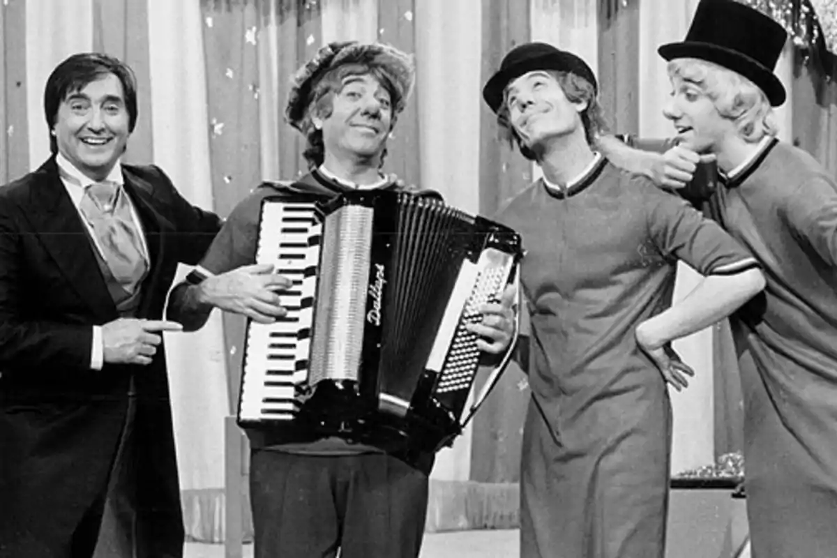 Un grupo de personas en blanco y negro, una de ellas tocando un acordeón y las otras tres posando alegremente.