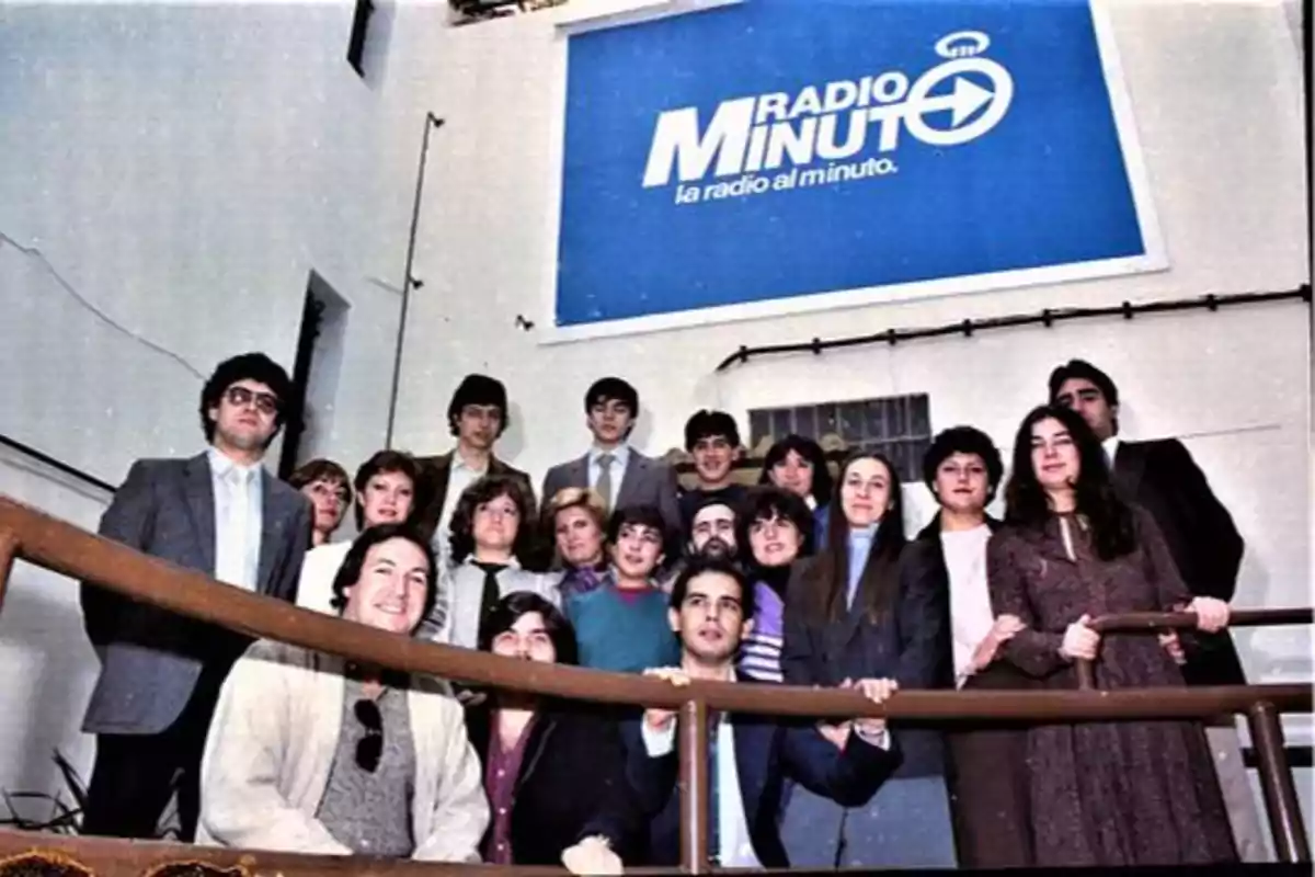 Un grupo de personas posando frente a un cartel que dice "Radio Minuto, la radio al minuto".