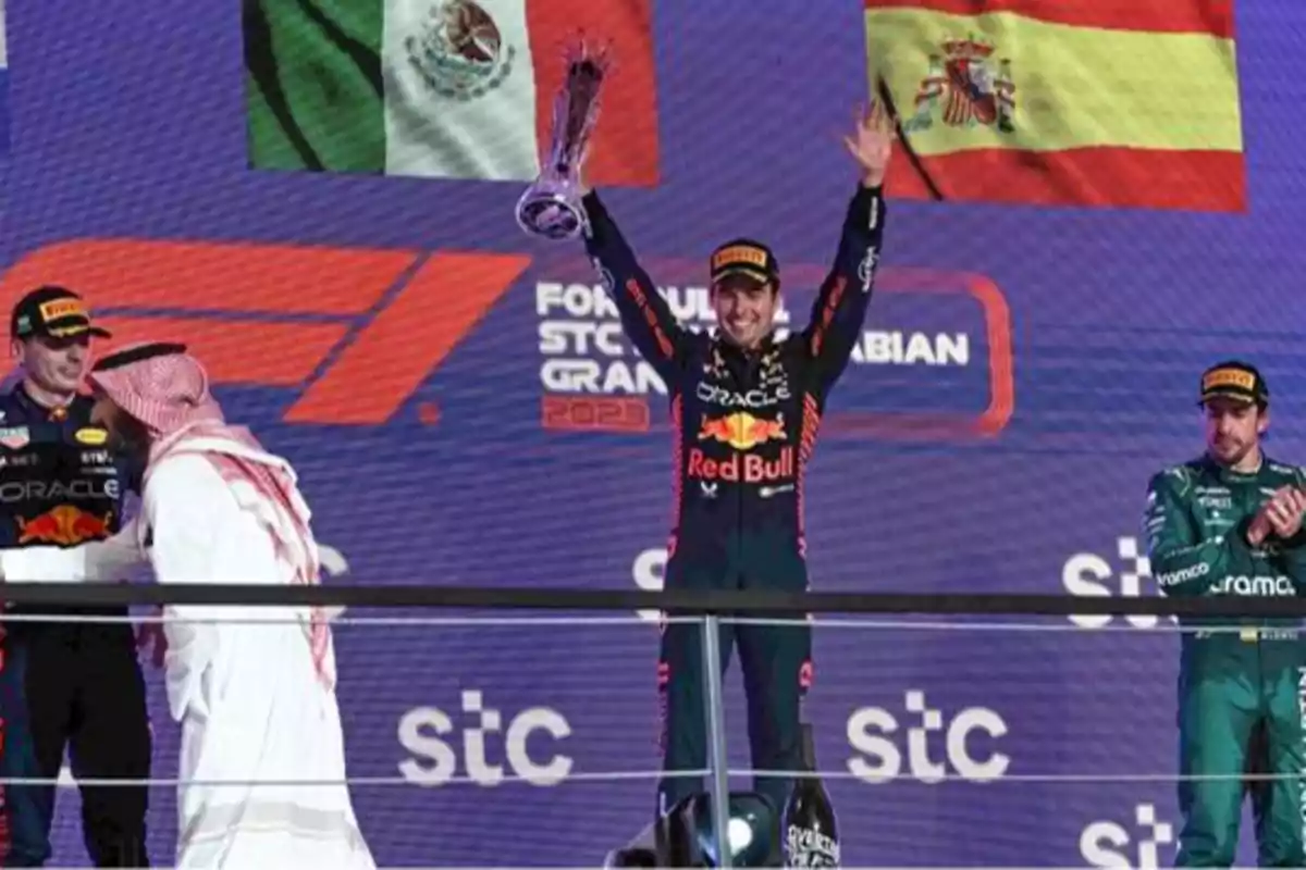 Piloto de Red Bull celebrando en el podio del Gran Premio de Arabia Saudita de Fórmula 1, con banderas de México y España en el fondo.