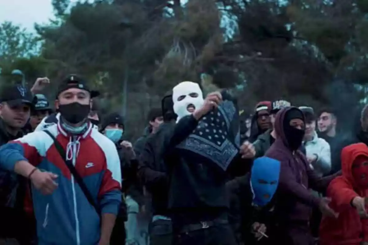 Un grupo de personas con máscaras y ropa casual se encuentra reunido al aire libre, algunos de ellos levantando las manos y mostrando un pañuelo.