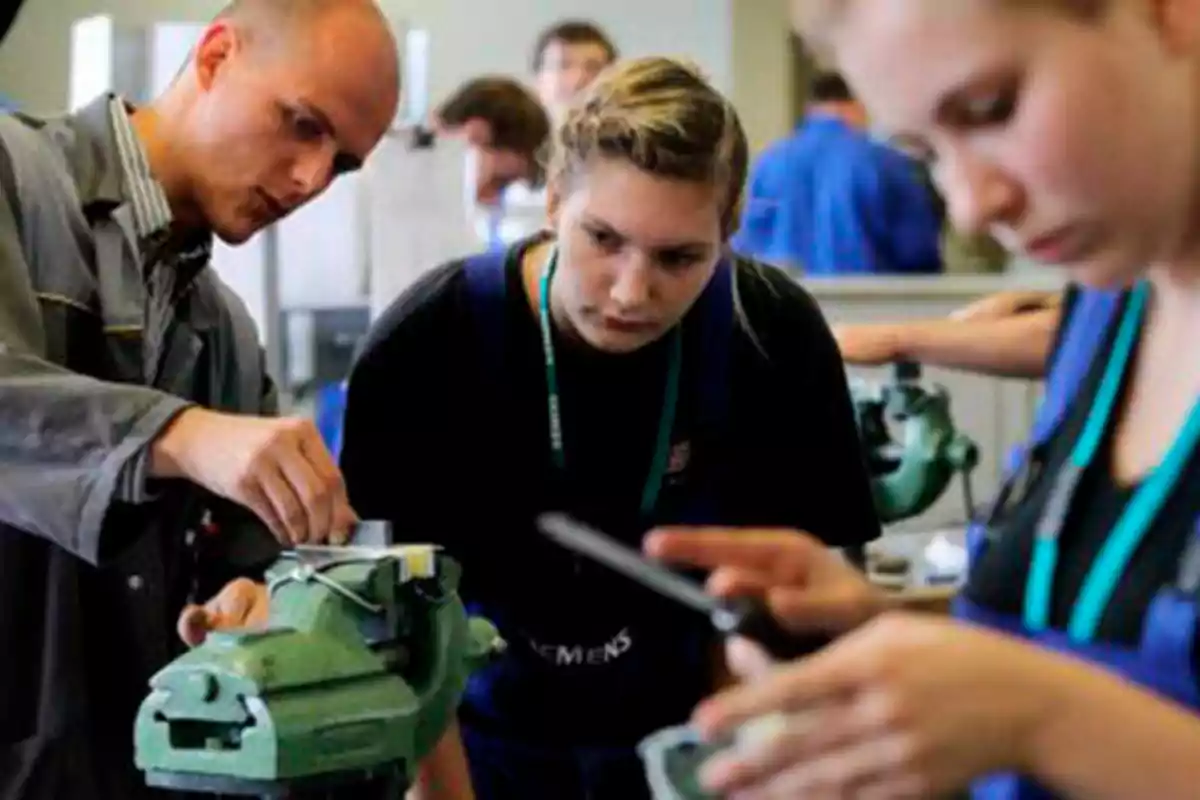 Un grupo de personas trabaja en un taller, enfocándose en una tarea mecánica con herramientas y equipos.
