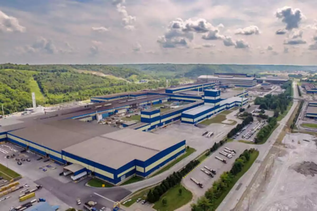 Vista aérea de una gran planta industrial rodeada de áreas verdes y caminos.