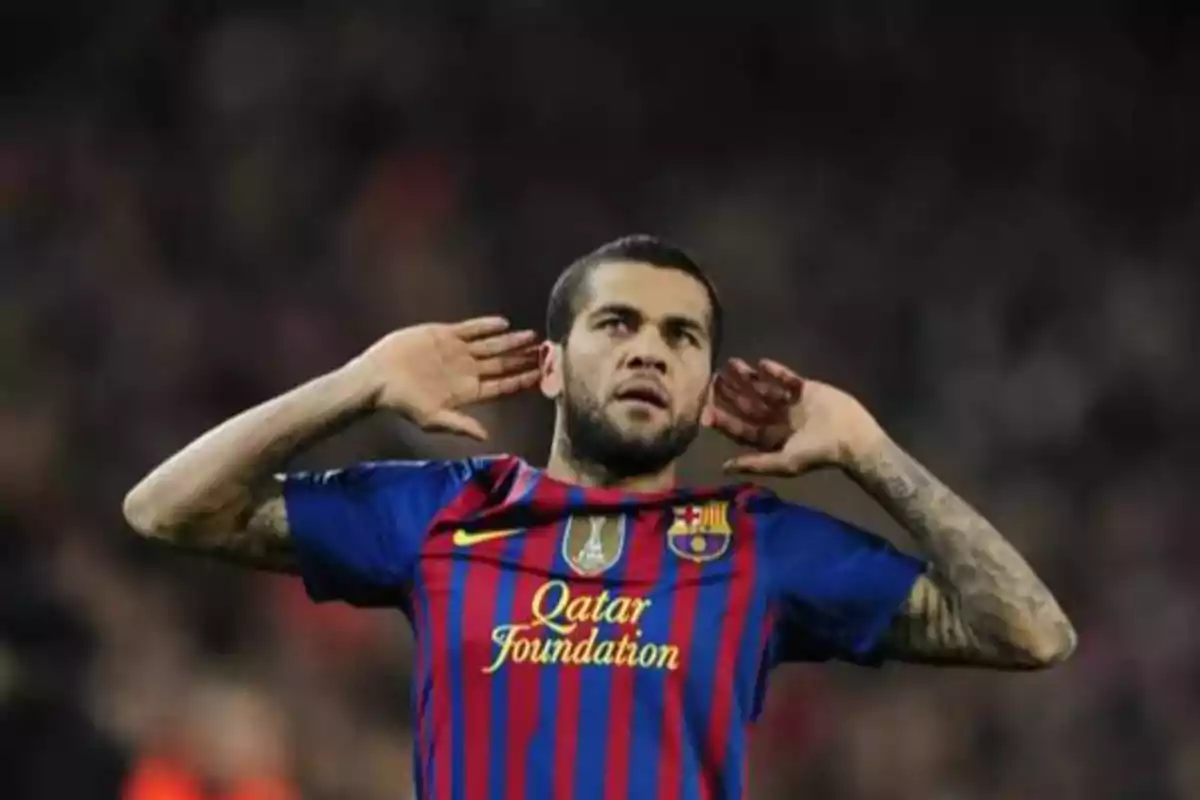 Jugador de fútbol con uniforme del FC Barcelona celebrando con las manos en las orejas.