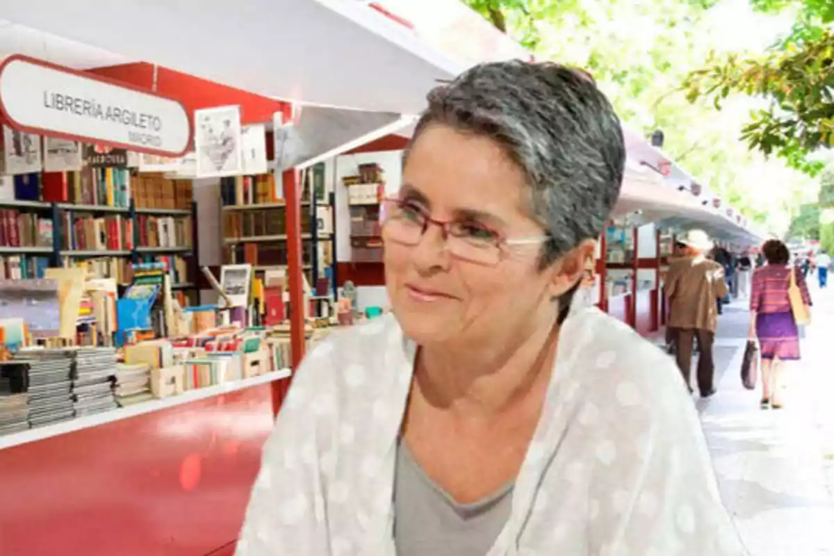 Mujer con gafas y cabello corto canoso en una feria de libros al aire libre.