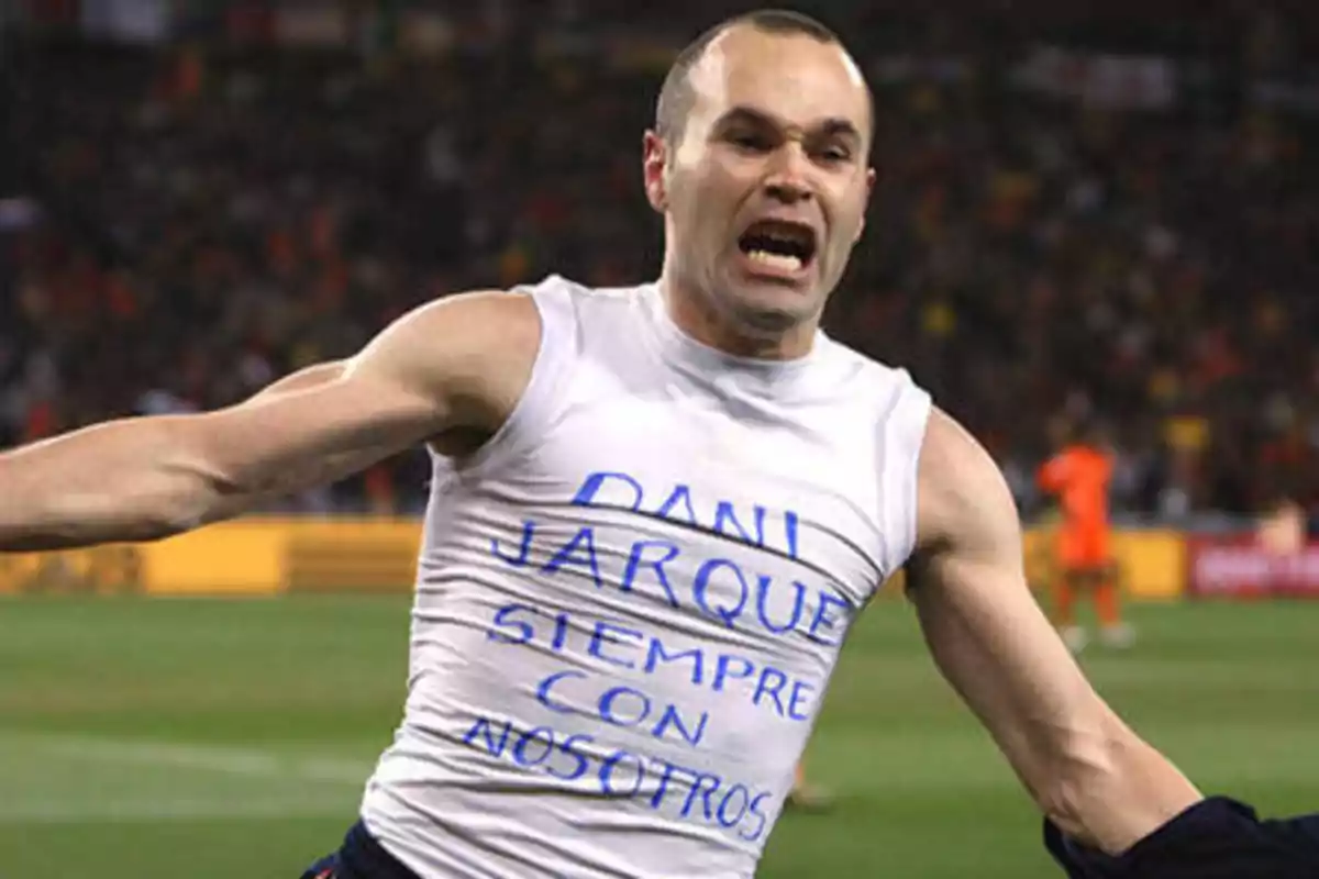 Un jugador de fútbol celebrando con una camiseta que tiene un mensaje escrito en honor a Dani Jarque.