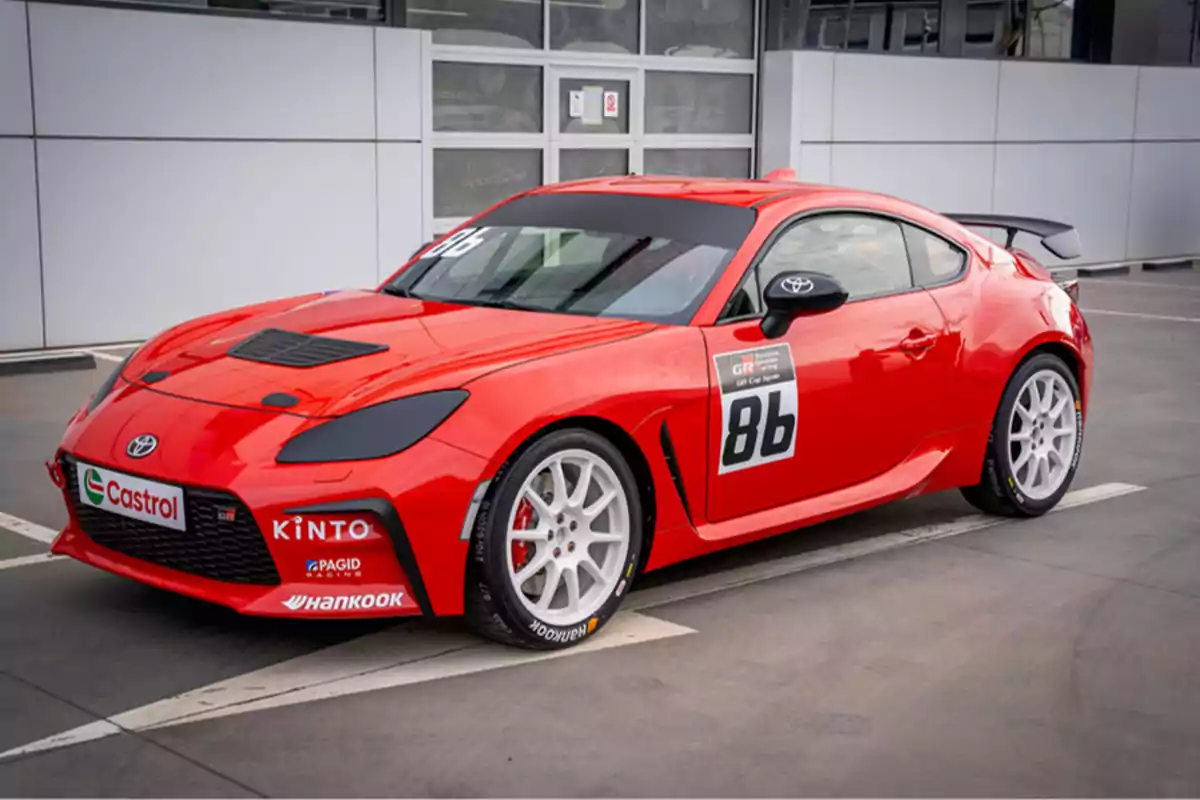 Un coche deportivo rojo con el número 86 en la puerta, estacionado frente a un edificio.