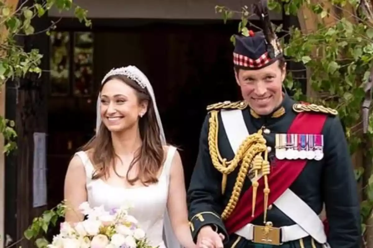 Pareja sonriente saliendo de una iglesia, la mujer lleva vestido de novia y ramo de flores, el hombre viste uniforme militar con medallas y gorra tradicional Pareja sonriente saliendo de una iglesia, la mujer lleva vestido de novia y ramo de flores, el hombre viste uniforme militar con medallas y gorra tradicional