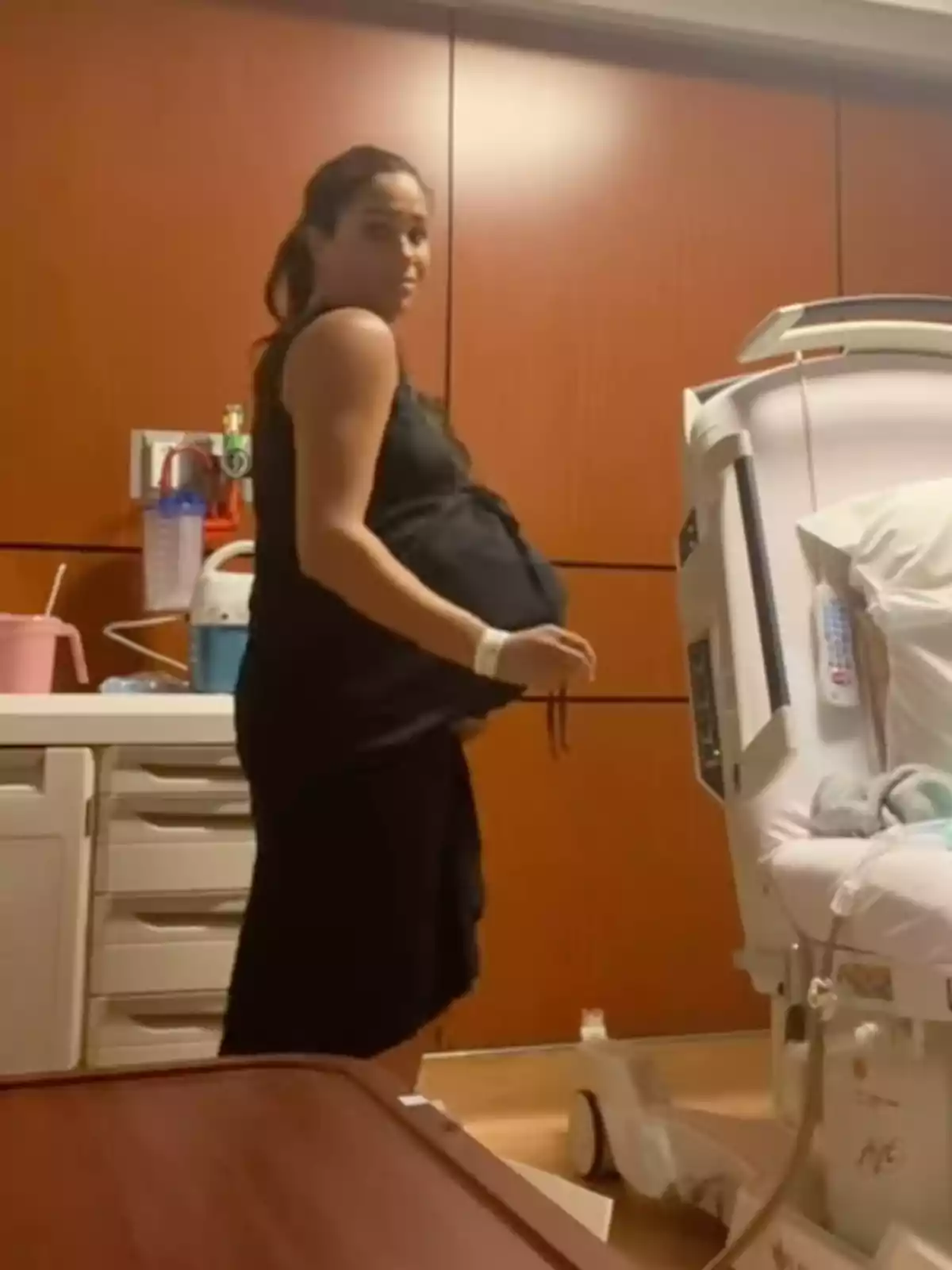 Meghan Markle standing pregnant in a hospital room next to a medical bed Meghan Markle standing pregnant in a hospital room next to a medical bed