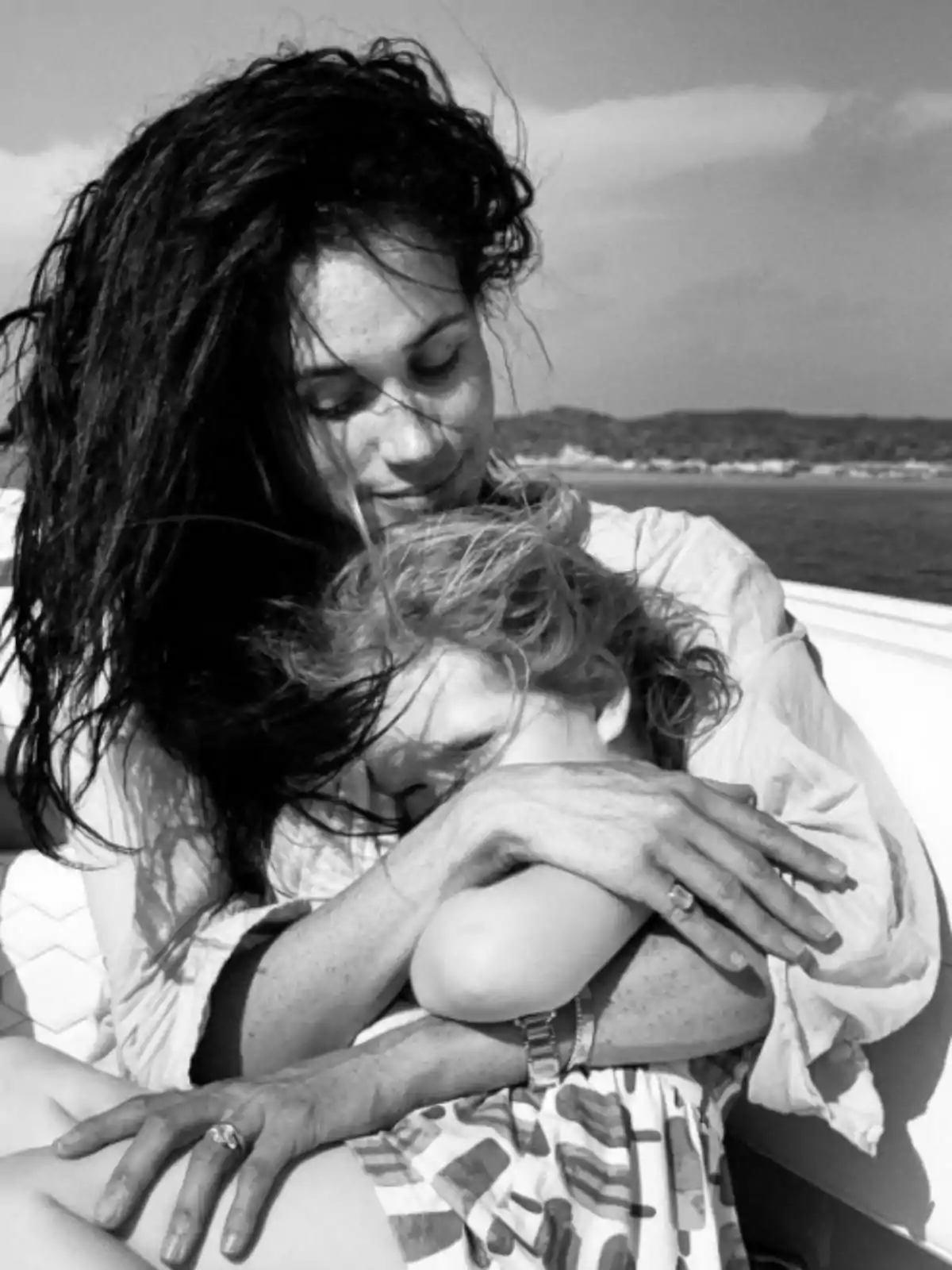 Meghan Markle abrazando tiernamente a una niña mientras están sentadas al aire libre en un día soleado Meghan Markle abrazando tiernamente a una niña mientras están sentadas al aire libre en un día soleado