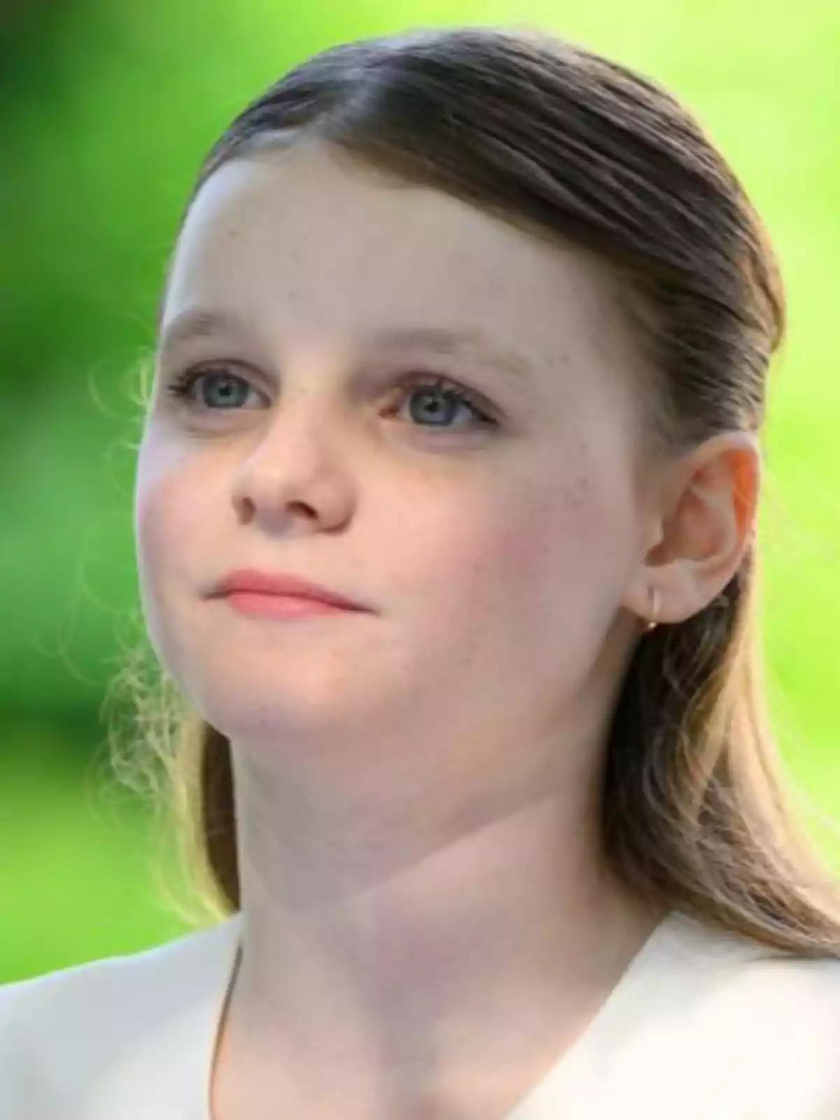Gabriella de Mónaco mirando hacia el frente con expresión serena y fondo verde difuminado Gabriella de Mónaco mirando hacia el frente con expresión serena y fondo verde difuminado