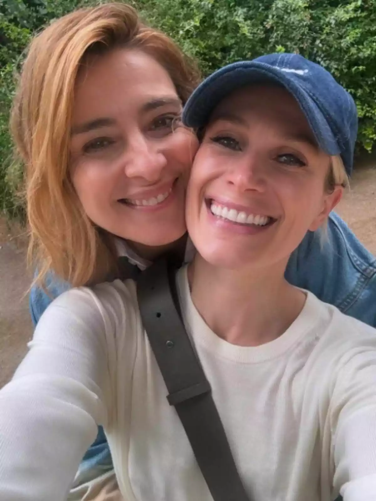 Sandra Barneda y Pascalle Paerel sonrientes posan para una selfie al aire libre, una lleva gorra azul y la otra tiene el cabello suelto. Sandra Barneda y Pascalle Paerel sonrientes posan para una selfie al aire libre, una lleva gorra azul y la otra tiene el cabello suelto.