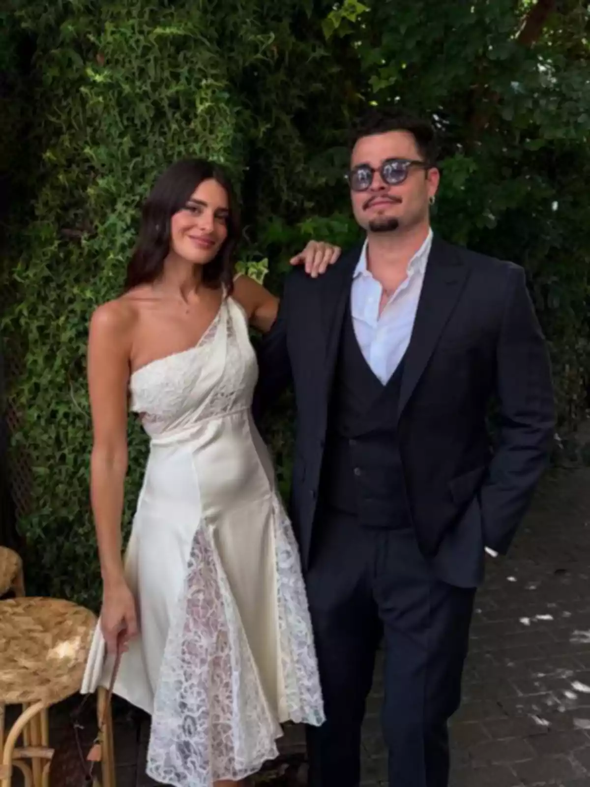Susana Molina con vestido blanco y Guille Valle con traje oscuro posan juntos al aire libre frente a un fondo de vegetación Susana Molina con vestido blanco y Guille Valle con traje oscuro posan juntos al aire libre frente a un fondo de vegetación
