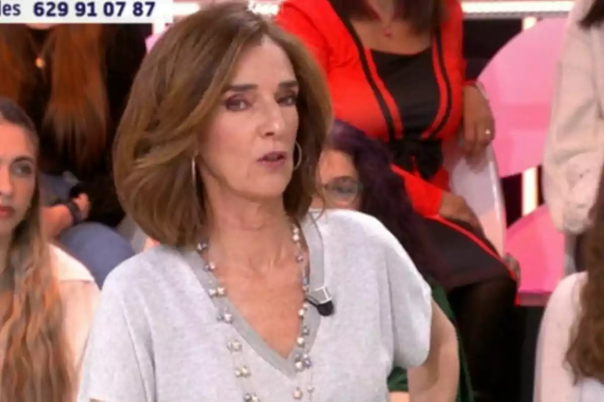 Paloma García-Pelayo con cabello castaño y un micrófono en la ropa está en un programa de televisión, con personas sentadas al fondo y un número de teléfono visible en la parte superior. Paloma García-Pelayo con cabello castaño y un micrófono en la ropa está en un programa de televisión, con personas sentadas al fondo y un número de teléfono visible en la parte superior.