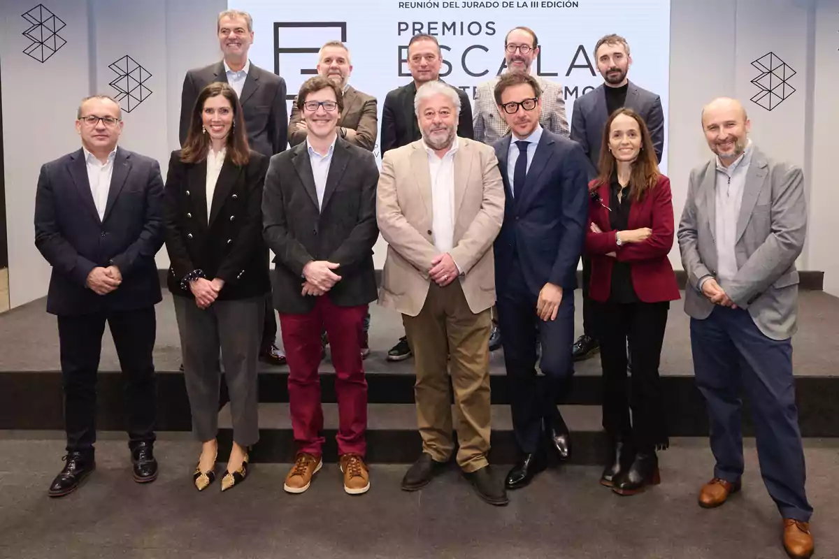 Un grupo de personas posando juntas en un escenario durante un evento de premios, con un cartel de fondo que dice "Premios Escala".