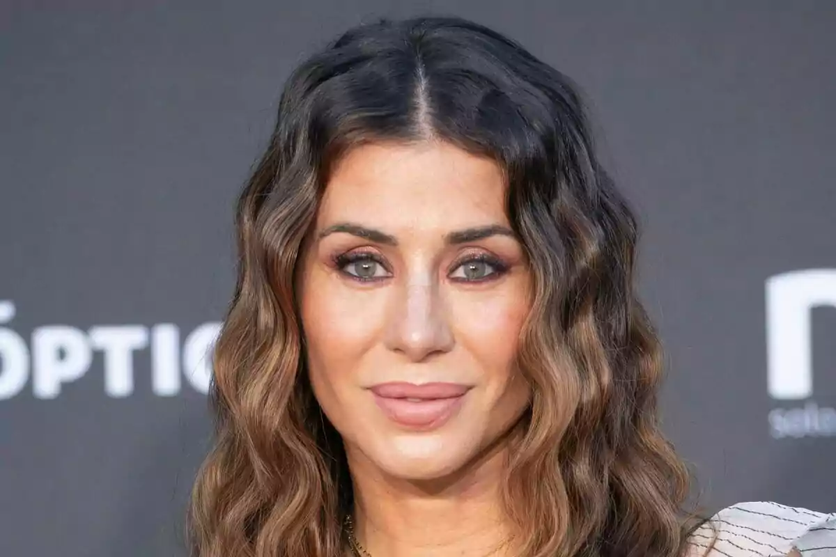 Elena Tablada con cabello ondulado y maquillaje sutil sonríe frente a un fondo oscuro.