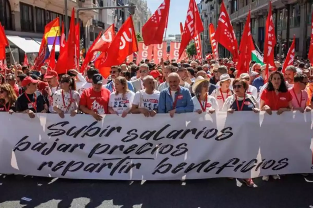 Un grupo de personas marcha por la calle sosteniendo una pancarta que dice Un grupo de personas marcha por la calle sosteniendo una pancarta que dice