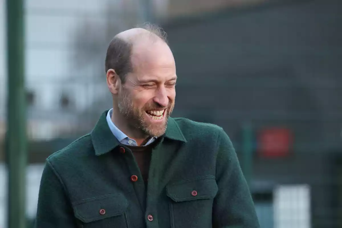El príncipe Guillermo con chaqueta verde sonríe al aire libre. El príncipe Guillermo con chaqueta verde sonríe al aire libre.