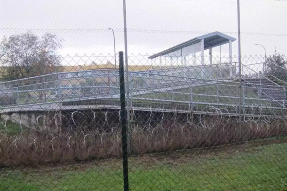Puente peatonal inaccesible rodeado completamente por una cerca de alambre y alambre de púas