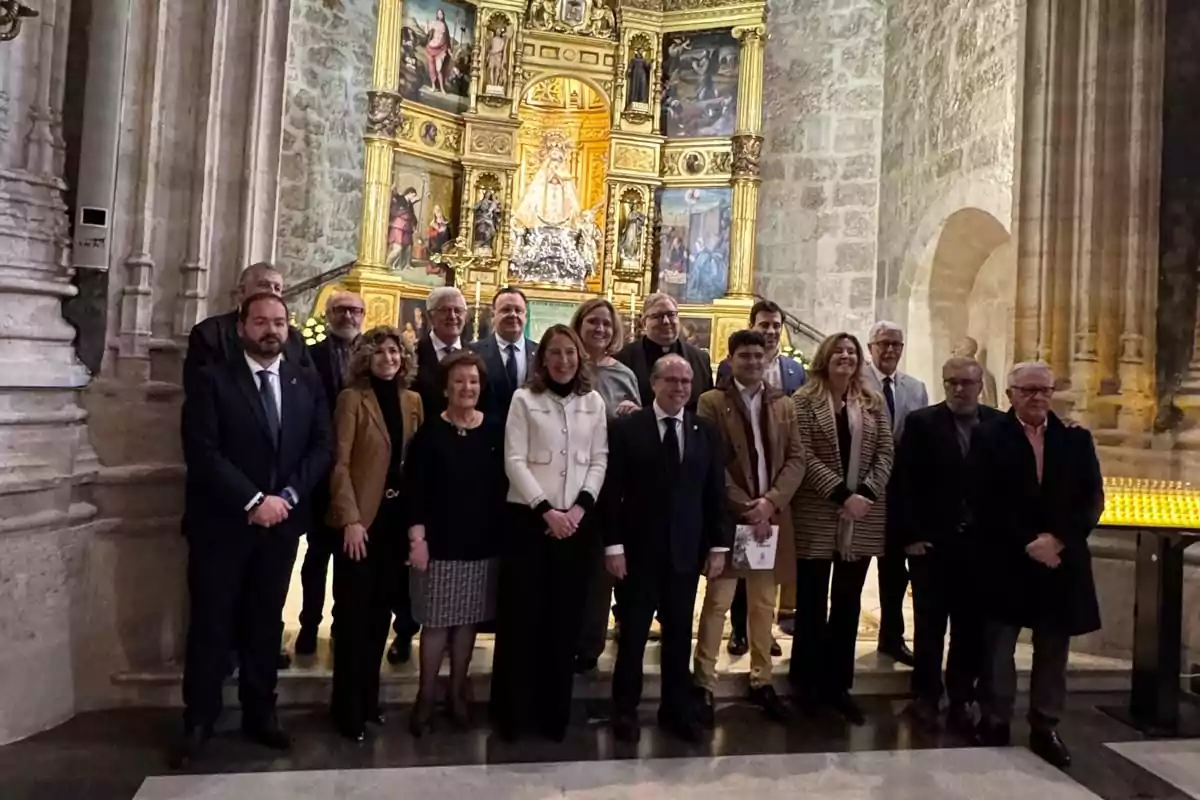 Un grupo de personas posando frente a un altar decorado con imágenes religiosas en el interior de una iglesia.