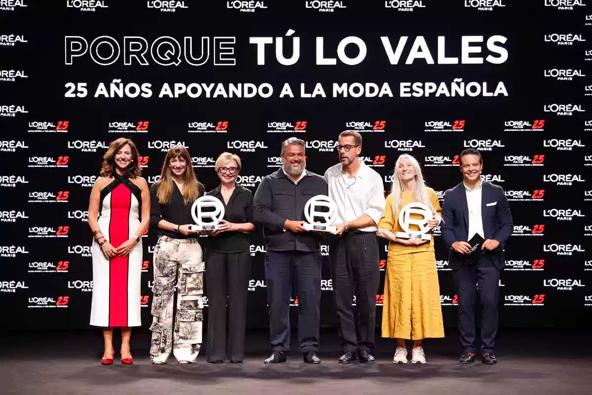 Un grupo de personas posando con trofeos en un evento de L'Oréal Paris que celebra 25 años apoyando a la moda española.